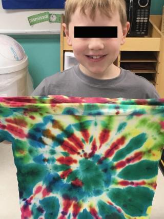 kid holding up tie dye shirt.